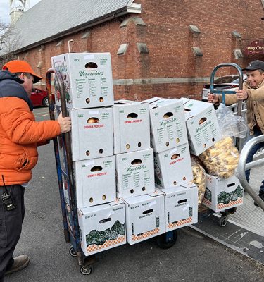The Farm Hub's Erick Saucedo and a volunteer for the Ulster County Immigrant Defense Network move boxes of produce into the Holy Cross Santa Cruz Episcopal Church that hosts a food pantry.